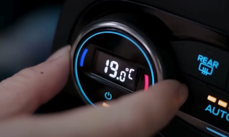A finger adjusts the car's climate control, setting the temperature to a crisp 19°C